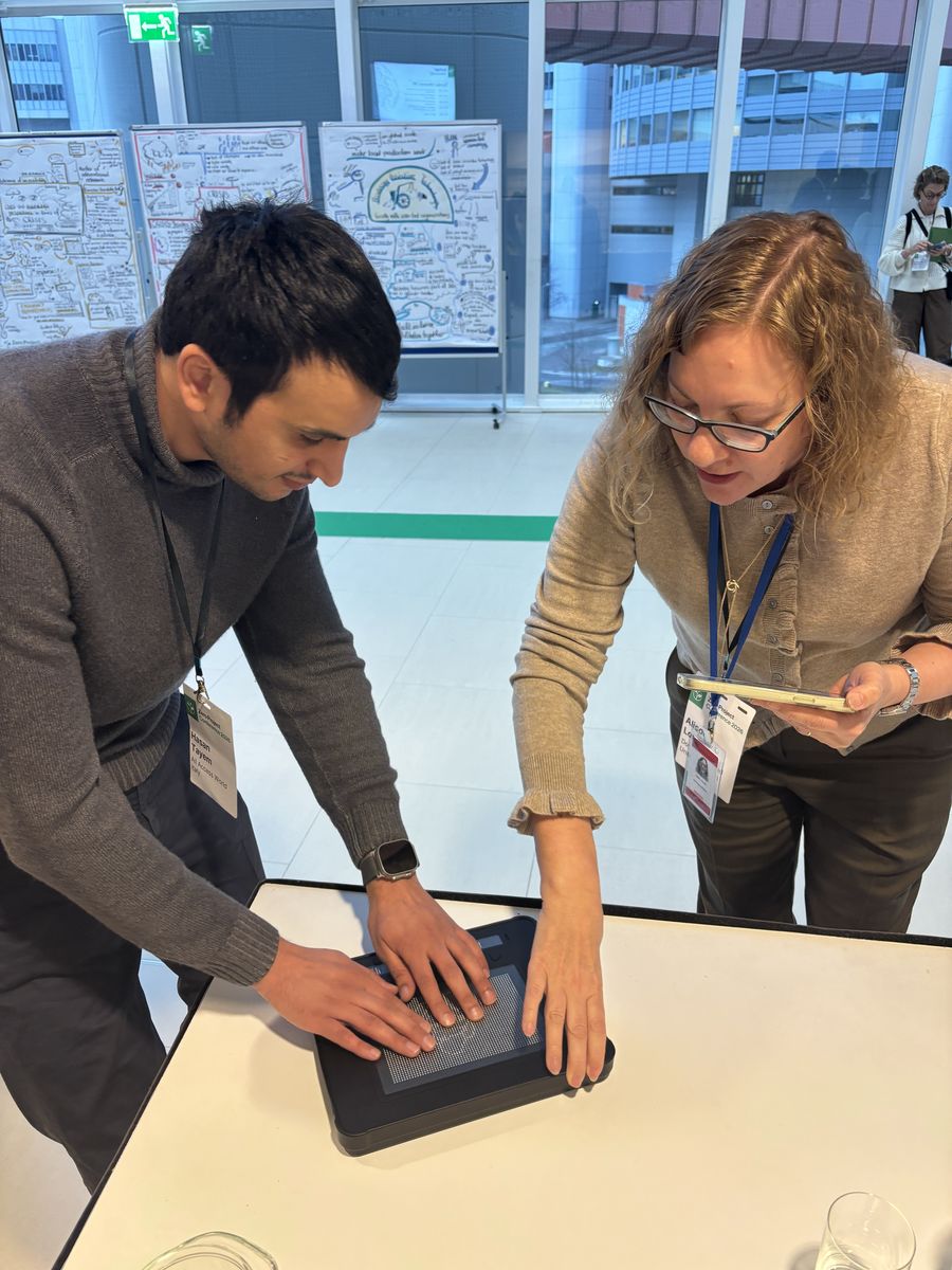 Hasan demonstrating an accessible tablet application to a colleague at a conference workshop session