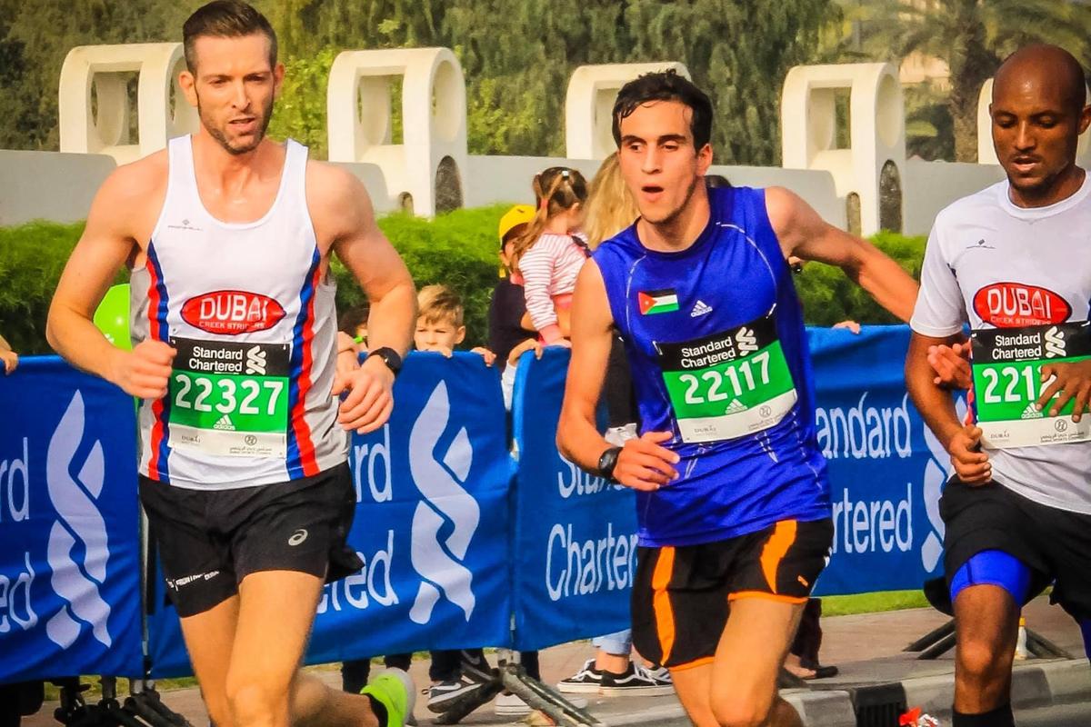 Hasan is running with two running guides beside him during the Dubai Marathon.