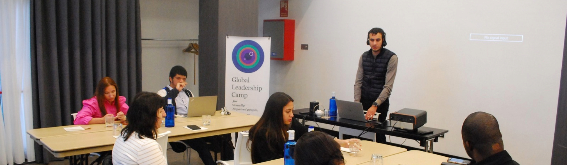 Hasan stands at the front of a professional workshop, leading a session for engaged participants at the Global Leadership Camp.